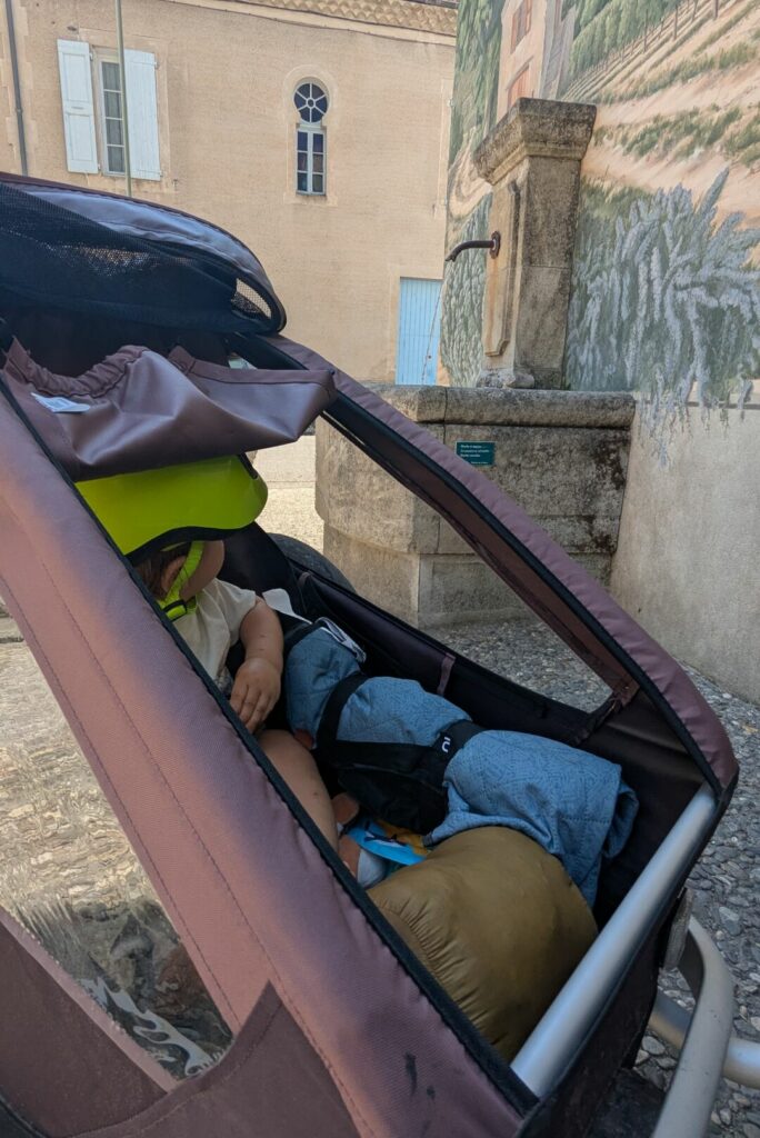 Remorque avec bébé devant une fontaine à Châtillon-en-Diois